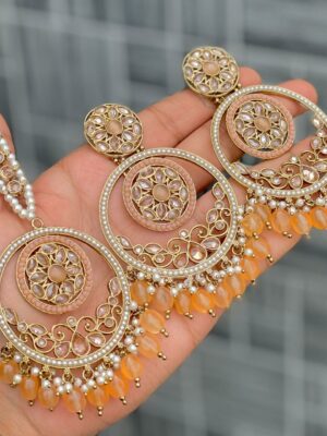 Beautiful premium quality reverse Ad melon orange coloured artificial stone, pearl earrings and tilak made of base metal alloy and gold plated and presented in hand holding